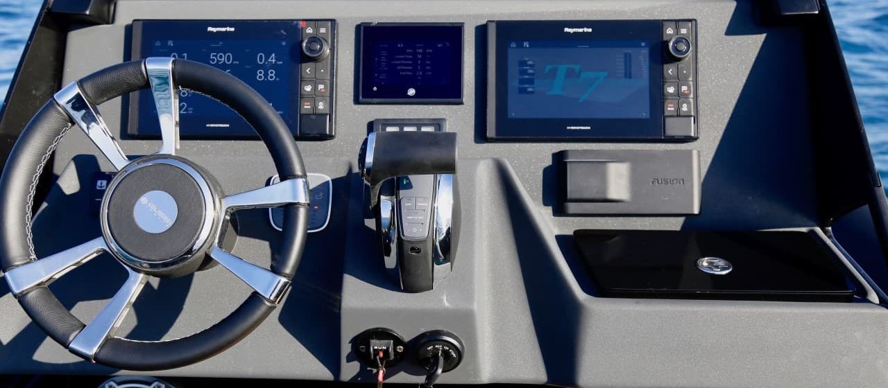 Skipper at the helm of the TechnoHull GT7, screens lit, open water ahead